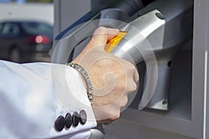 A man`s hand picks up a charging gun at a stationary charging station for electric vehicles from the power grid in the city, envir