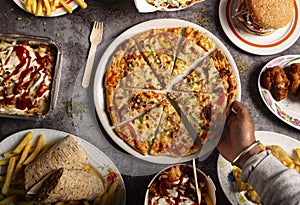 A man`s hand picks up a slice of pizza at the table in the fast food restaurant