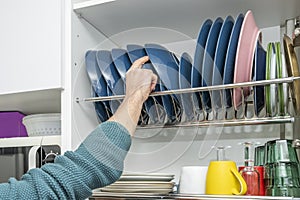 Man's hand placing blue dishes in the drainer