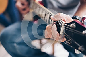 Man`s hand the playing an electric guitar.