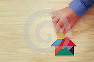 Man's hand pointing at house made from tangram puzzle