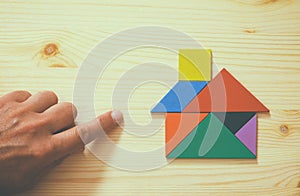 Man's hand pointing at house made from tangram puzzle