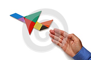 Man's hand pointing at plane made from square tangram puzzle