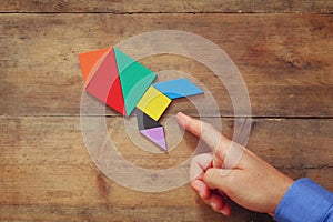 Man's hand pointing at rocket made from square tangram puzzle