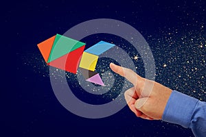 Man's hand pointing at rocket made from tangram puzzle