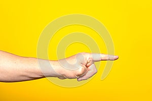 Man& x27;s hand pointing at something with the index finger, isolated on yellow background. Choice gesture. Side view