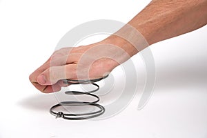 A man`s hand presses on a spring, on a white background.Exert pressure