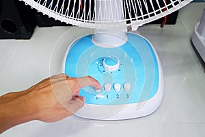 Man's hand pressing a fan button and turning the timer