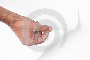 Man`s hand pull up  a bottom corner of a white paper sheet to uncover a neutral foreground with clipping path and copy space for