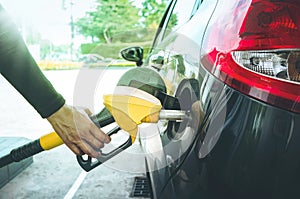 Man`s hand pumping gasoline fuel in car at gas station.