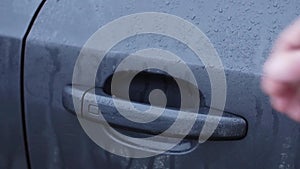 Man's hand push wet handle of door, open car. Close up. Rainy day