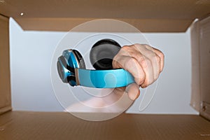 A man`s hand puts the headphones in a cardboard moving box. Wireless stereophonic device for personal listening to audio