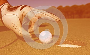 Man`s hand putting golf ball in hole