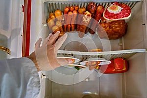 A man`s hand reaches for the food in the fridge upside down