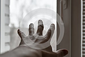 Man`s hand reaches for  window. Concept: asking for help, depression, finding way out, freedom, sharing your feelings. Hand