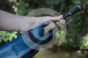 A man`s hand removes the baitcasting rod from the case photo