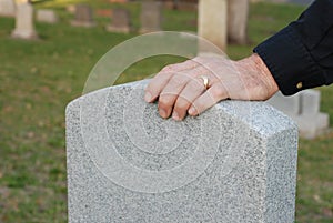 Man's hand resting on headstone