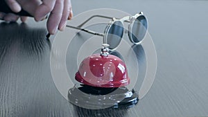 A man`s hand rings a bell at the front desk.
