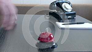 A man`s hand rings a bell at the front desk. Vintage.