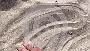 Man`s hand scatters sand through his fingers.