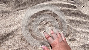 Man`s hand scatters sand through his fingers. Hand movement