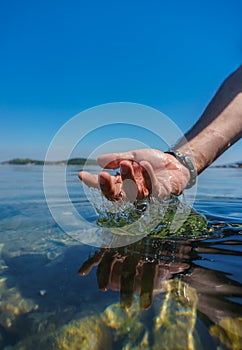 Man`s hand in the sea. Water and drop splashing. Hand, sea, reflection. Turkey