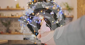 Man& x27;s hand sets fire to a sparkler on the background of a Christmas tree. First-person view. Sparks, flames, new