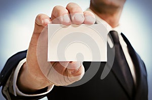 Man's hand showing business card. Black suit and tie.