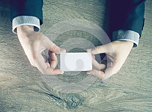 Man`s hand showing business card - closeup shot on dark wooden background