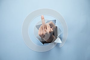 Man`s hand showing middle finger on blue background