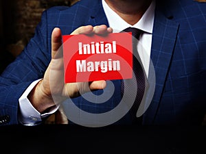 Man`s hand showing red business card with phrase Initial Margin - closeup shot on grey background