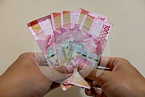 Man's Hand showing rupiah money isolates on cream background photo