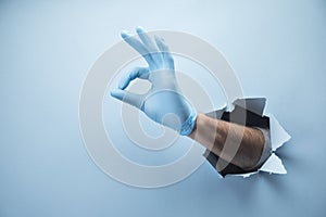 Man`s hand shows ok in gloves on a blue background