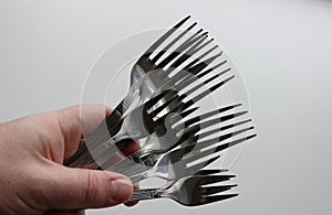 A man's hand squeezes a bunch of cake and table forks from one set