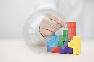 Man\'s hand stacking colorful wooden blocks