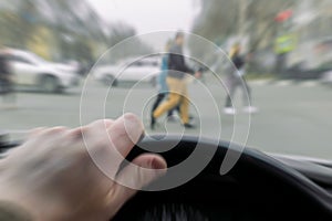 A man`s hand on the steering wheel of a car while braking at a pedestrian crossing