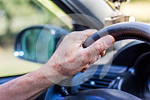 Man`s hand on steering wheel of a car. Driving on the road_