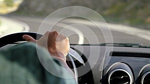 Man`s hand on the steering wheel driving a car in the long road along mountains in slow motion. 3840x2160