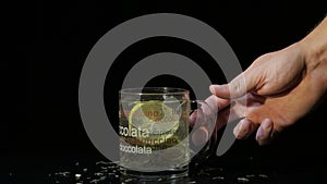 Man`s hand take a glass cup with Green tea. Glass cup with organic dry green tea leaves and slice of lemon which are floating insi