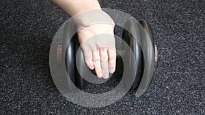 Man`s hand takes a heavy dumbbell in gym, close up indoor sport guy