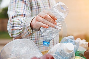 Man`s hand throwing clear transparent recyclable plastic bottle in garbage bin