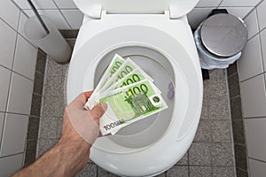 Man`s Hand Throwing Hundred Euro Notes In Toilet