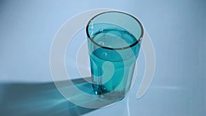 A man`s hand throws a soluble pill into blue glass of water. The tablet fizzes and dissolves. Healthycare and medicine concept