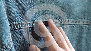 A man's hand touches blue denim, checking its quality before buying in an outlet clothing store.