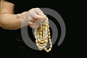 A man`s hand touches a wooden Buddhist rosary on a black  background. Close-up, banner, copy space