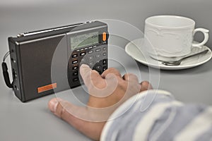 Man`s hand tuning into a small radio receiver