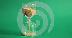 Man`s hand turns the hourglass on green background. Time and transience concept.