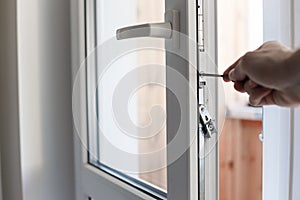 Man`s hand uses screwdriver for adjustment of hardware of the uPVC door mechanism