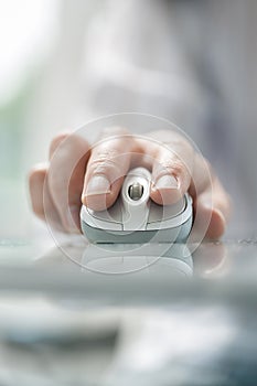 Man`s hand using cordless mouse on glass table.