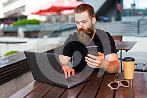 Man`s hand using smart phone in modern interior street cafe, busy business man using cell phone and online technologies. Young